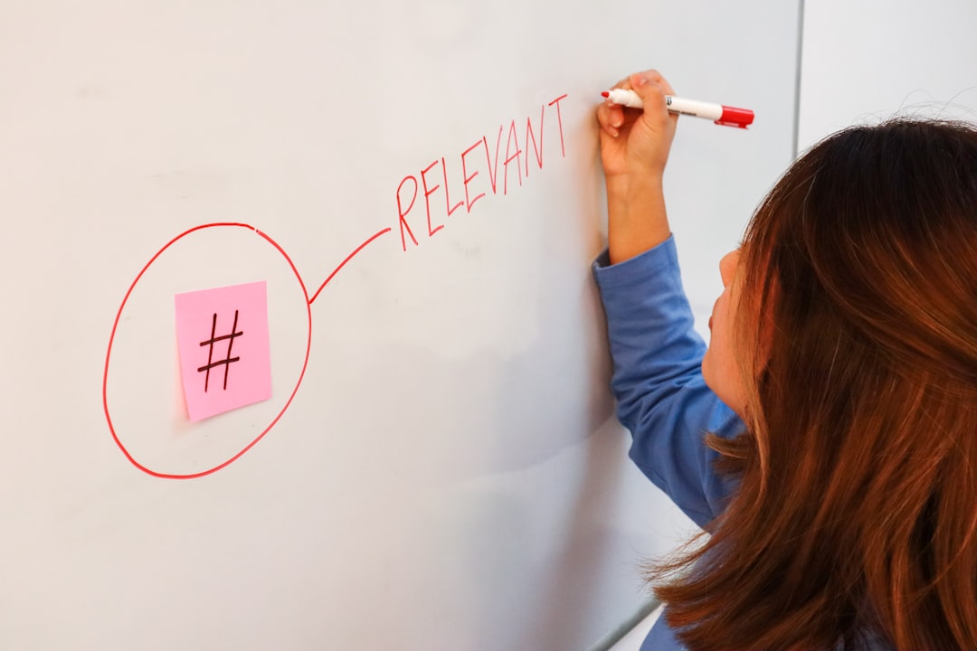 A woman writing the word relevant next to a sticky note with a hashtag on it