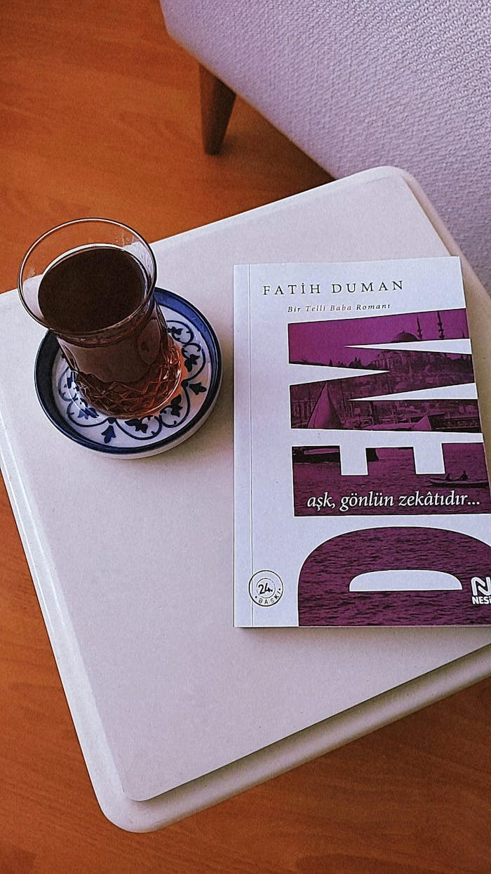 A book by Fatih Duman with a glass of tea on a small table.